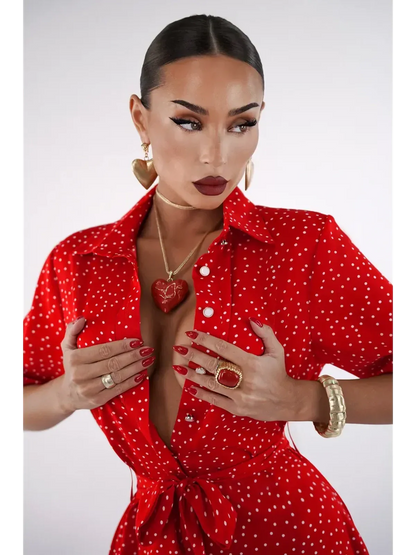 Woman wearing a vibrant red polka dot midi dress with a V-neckline and cinched waist, showcasing bold jewelry.