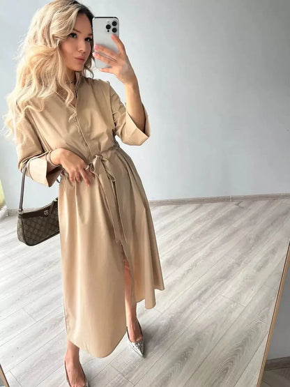 Woman wearing a Studio Beige Midi Dress with a belt, showcasing minimalist style and elegant comfort in a modern setting.