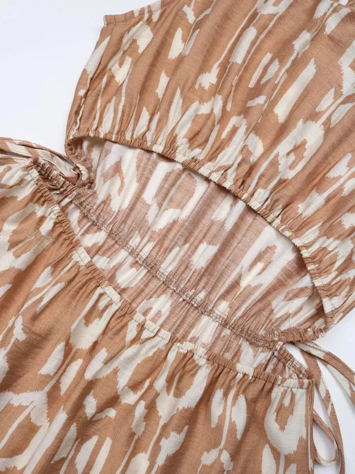 Close-up of the Nomad Tiered Midi Dress showcasing its tiered design and bohemian geometric print in soft beige tones.