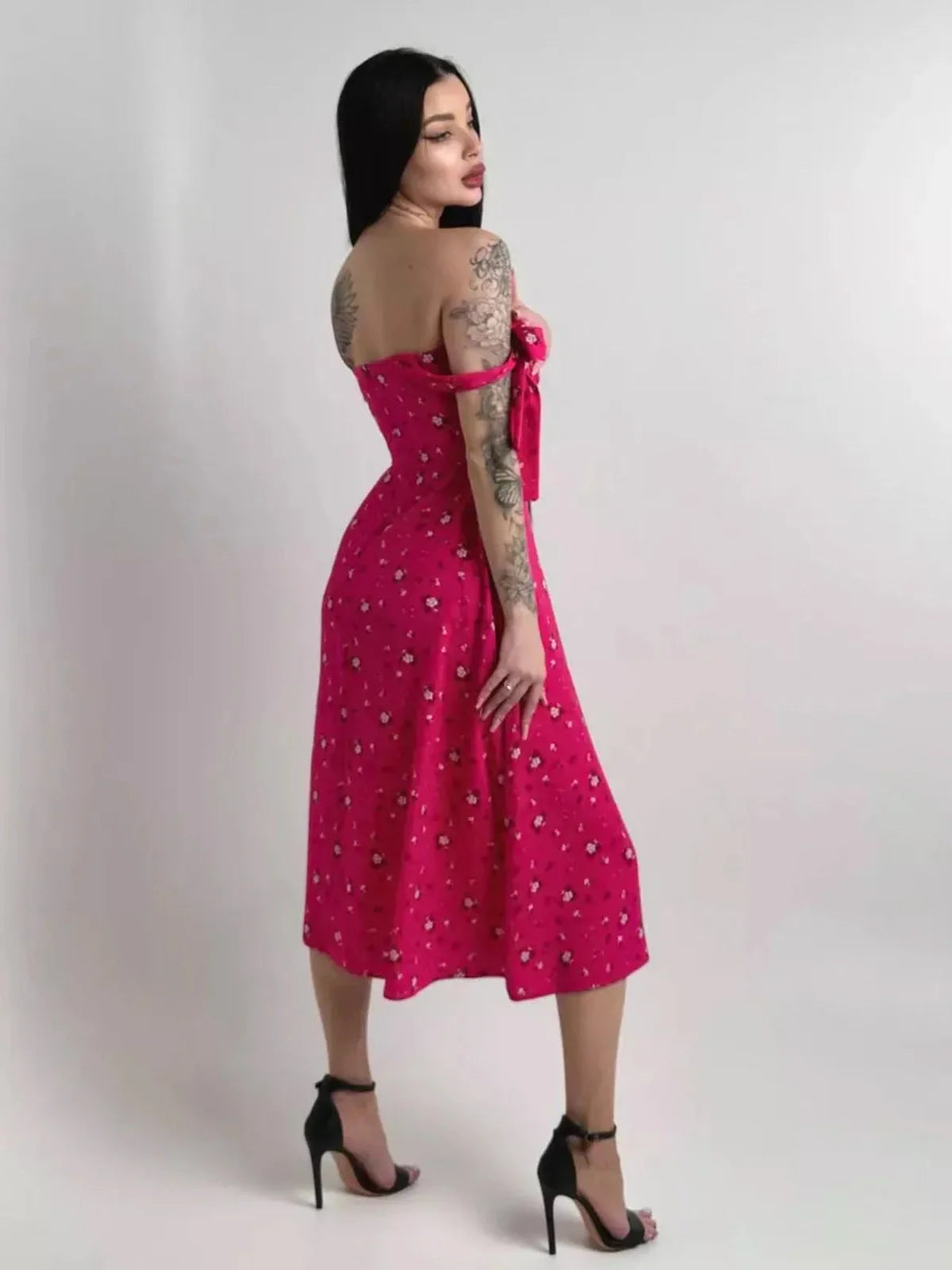 Woman in a pink floral midi dress with adjustable ties, showcasing a romantic and feminine style perfect for summer events.