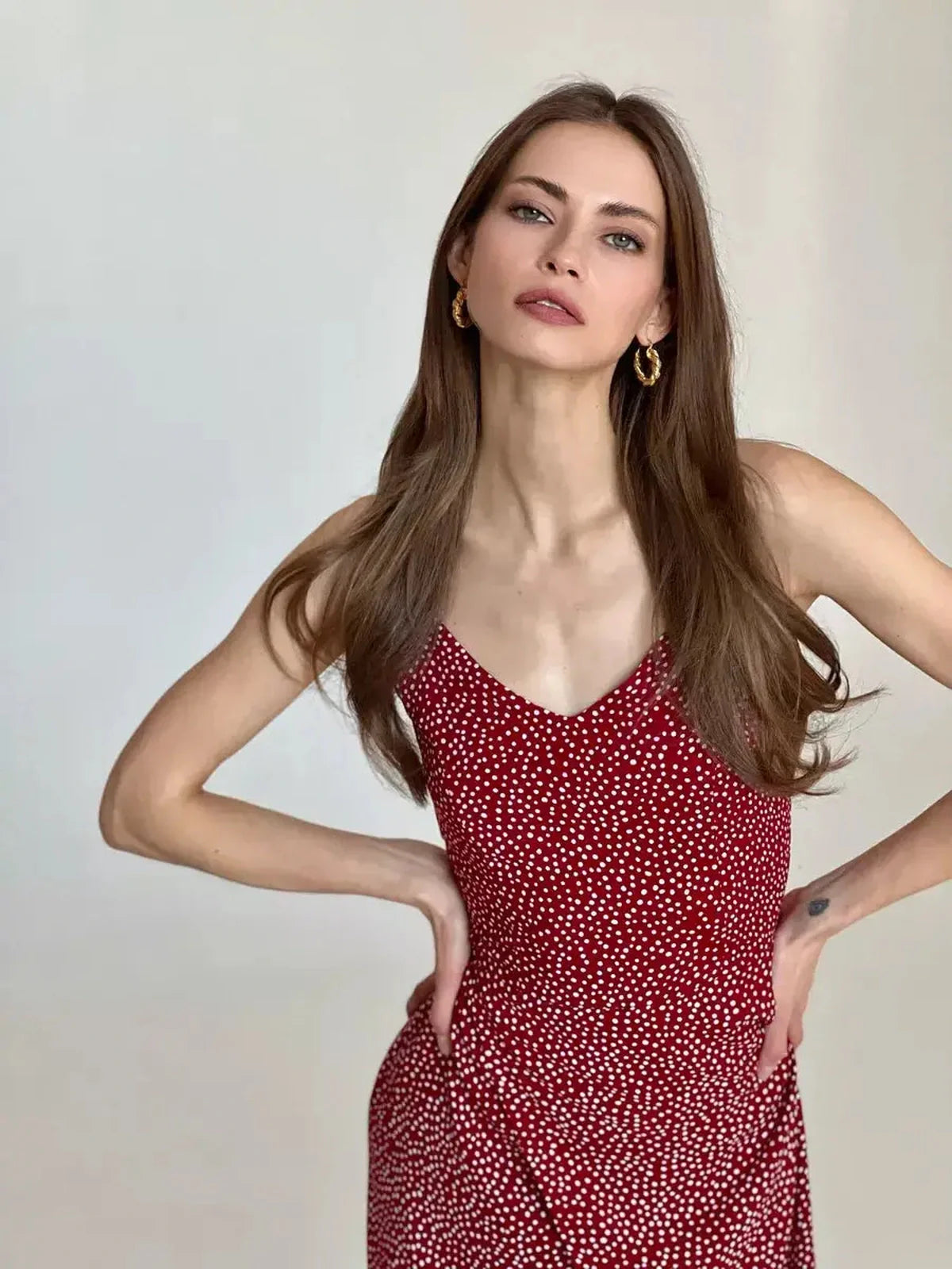 Model showcasing the Cherry Dots Midi Dress, featuring a red fabric with white polka dots and a flattering silhouette.