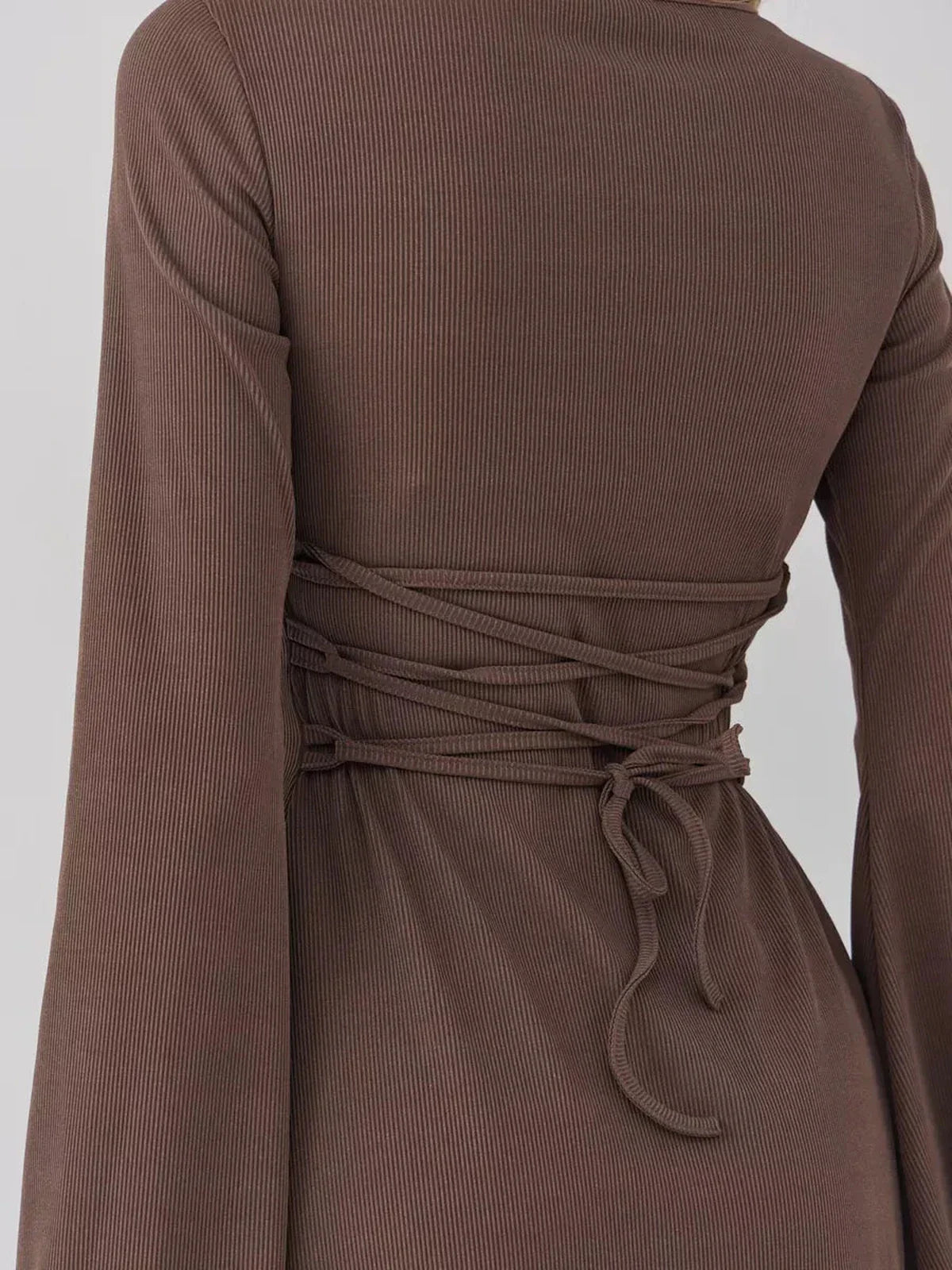 Back view of a stylish brown mini dress featuring ribbed texture and adjustable waist ties for a flattering fit.