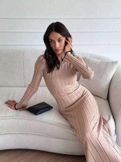 Model showcasing the elegant Sahara Curve Maxi Dress in Sandstone Beige, styled with a chic handbag.