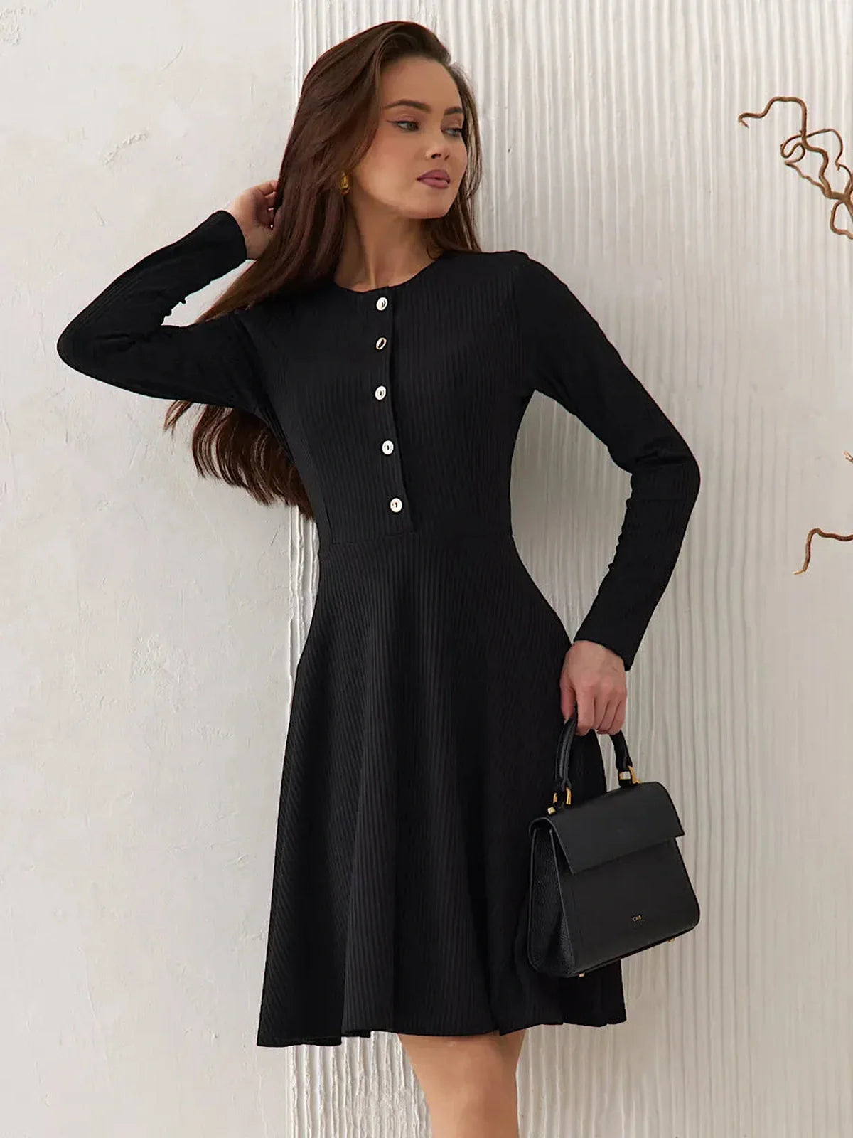 Elegant black mini dress with long sleeves, round neckline, and statement buttons, perfect for various occasions.