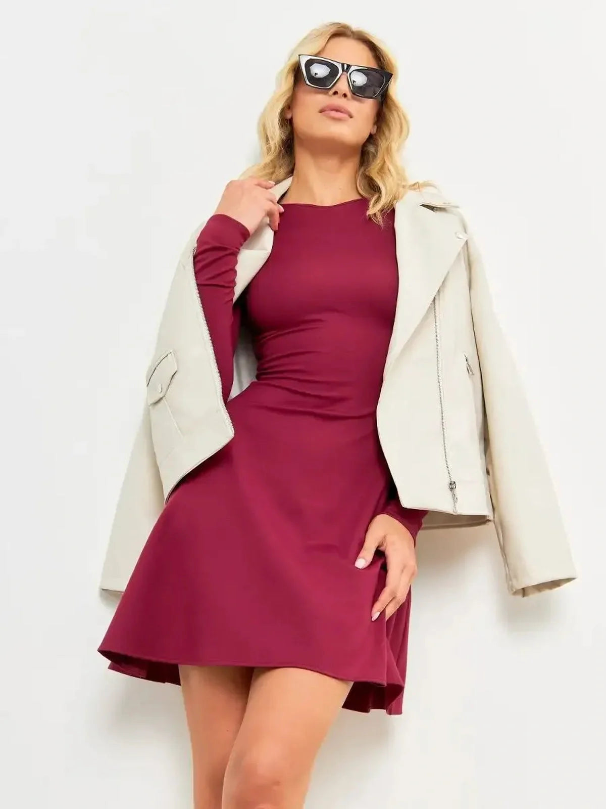 Woman in a wine flare mini dress paired with a stylish jacket and sunglasses, exuding elegance and confidence.