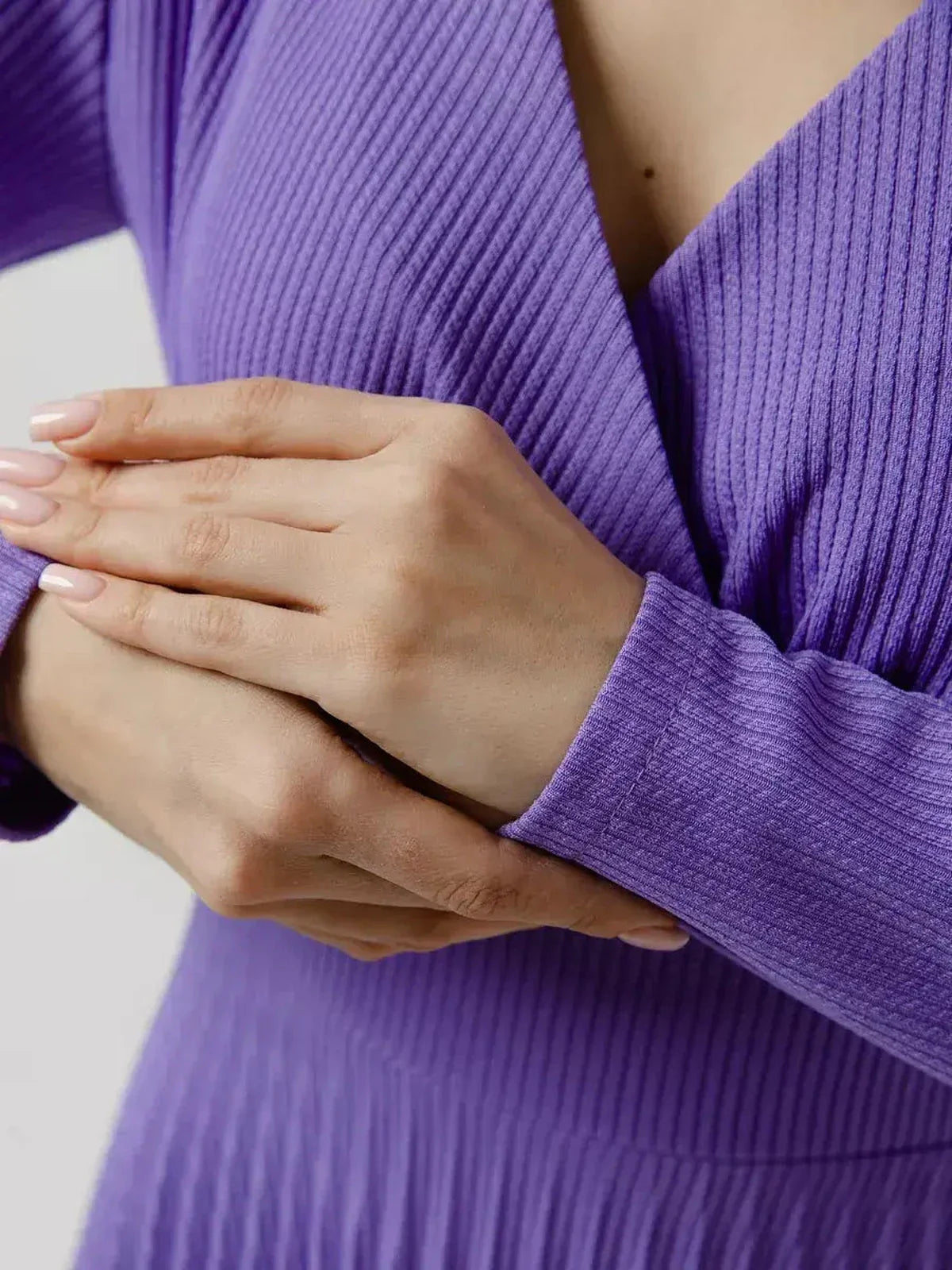 Close-up of hands adjusting the sleeve of a Luxe Pleated Midi Dress in rich violet, showcasing its elegant design.