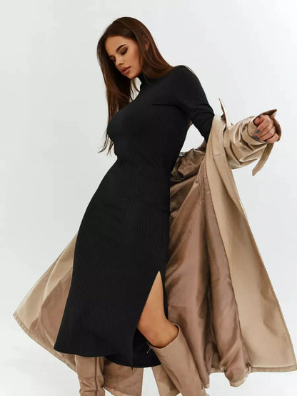 Stylish woman models a black Sculpted Rib Midi Dress with a side slit and long sleeves, paired with a chic coat.