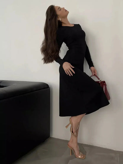 Elegant woman in a black Luxe Lace Midi Dress styled with heels and a handbag, exuding sophistication and femininity.