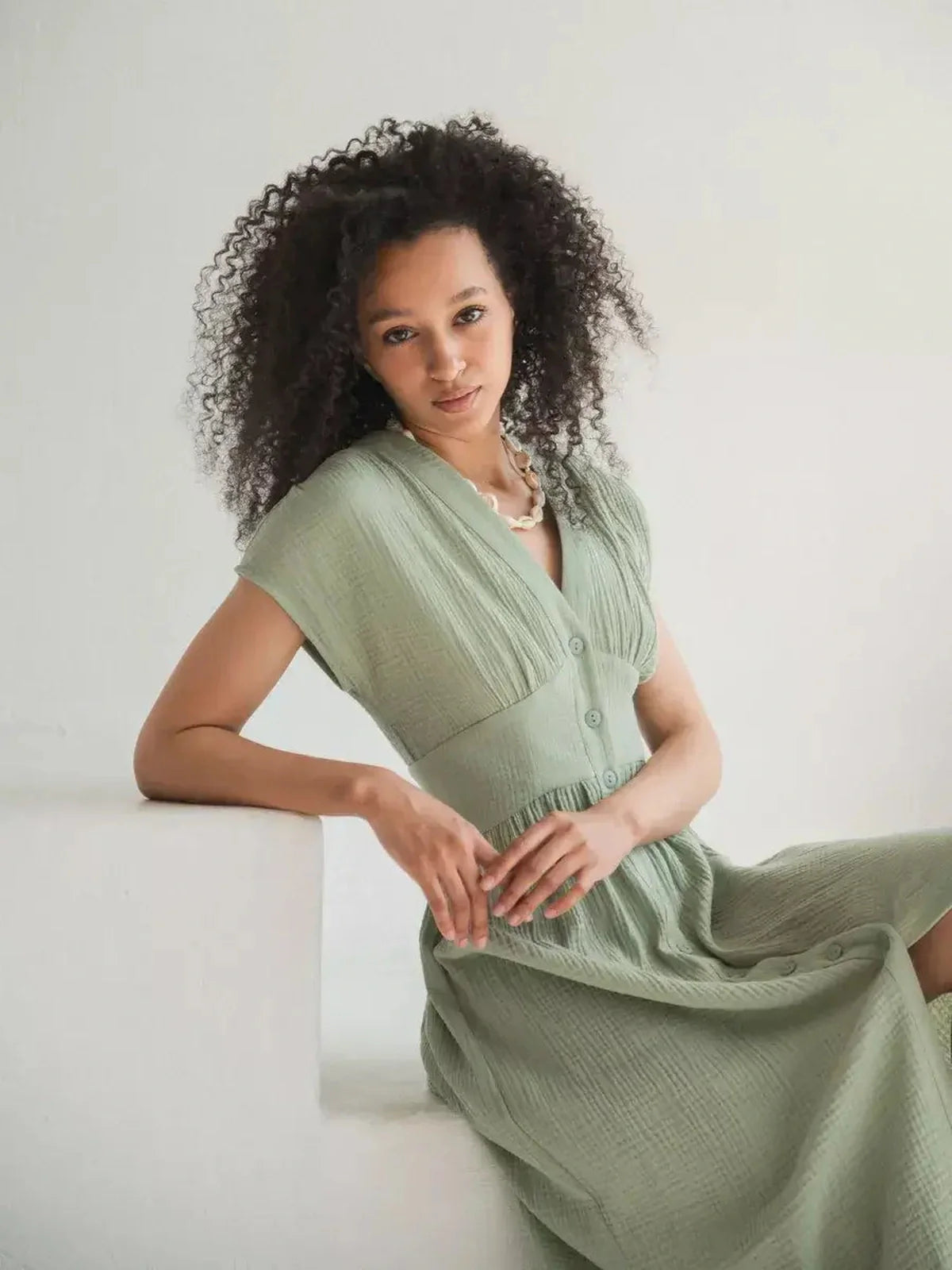 Woman in a khaki green Verdana Midi Dress with corset-inspired fit, perfect for summer and casual-chic occasions.