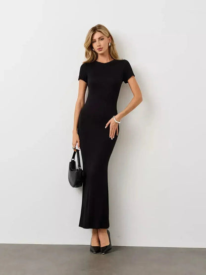 Model wearing a Noir Curve Maxi Dress in iconic black, featuring a sculpted silhouette and flared hem.