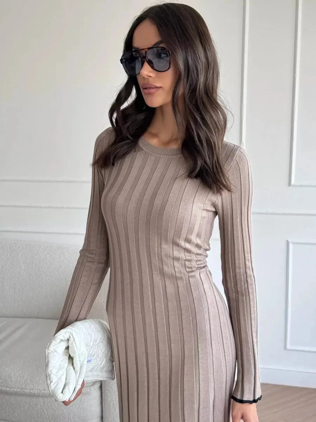 Model wearing a beige ribbed knit Contour Maxi Dress, showcasing its elegant long sleeve design and chic sunglasses.