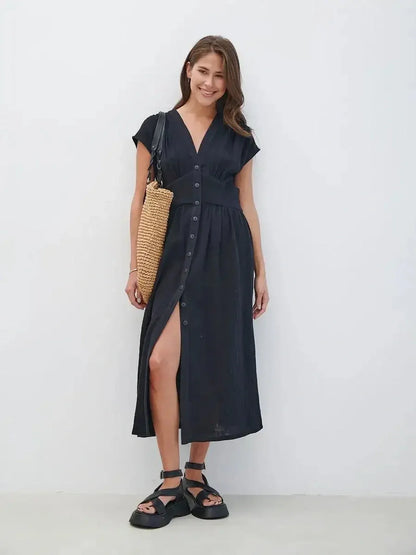 Model wearing the Sable Grace Midi Dress in black, featuring a V-neck, button details, and a stylish side slit for summer elegance.