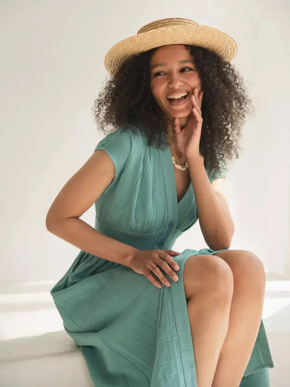 Model wearing a sea-green Veranda Midi Dress, featuring a V-neckline and corset waist, styled with a straw hat.