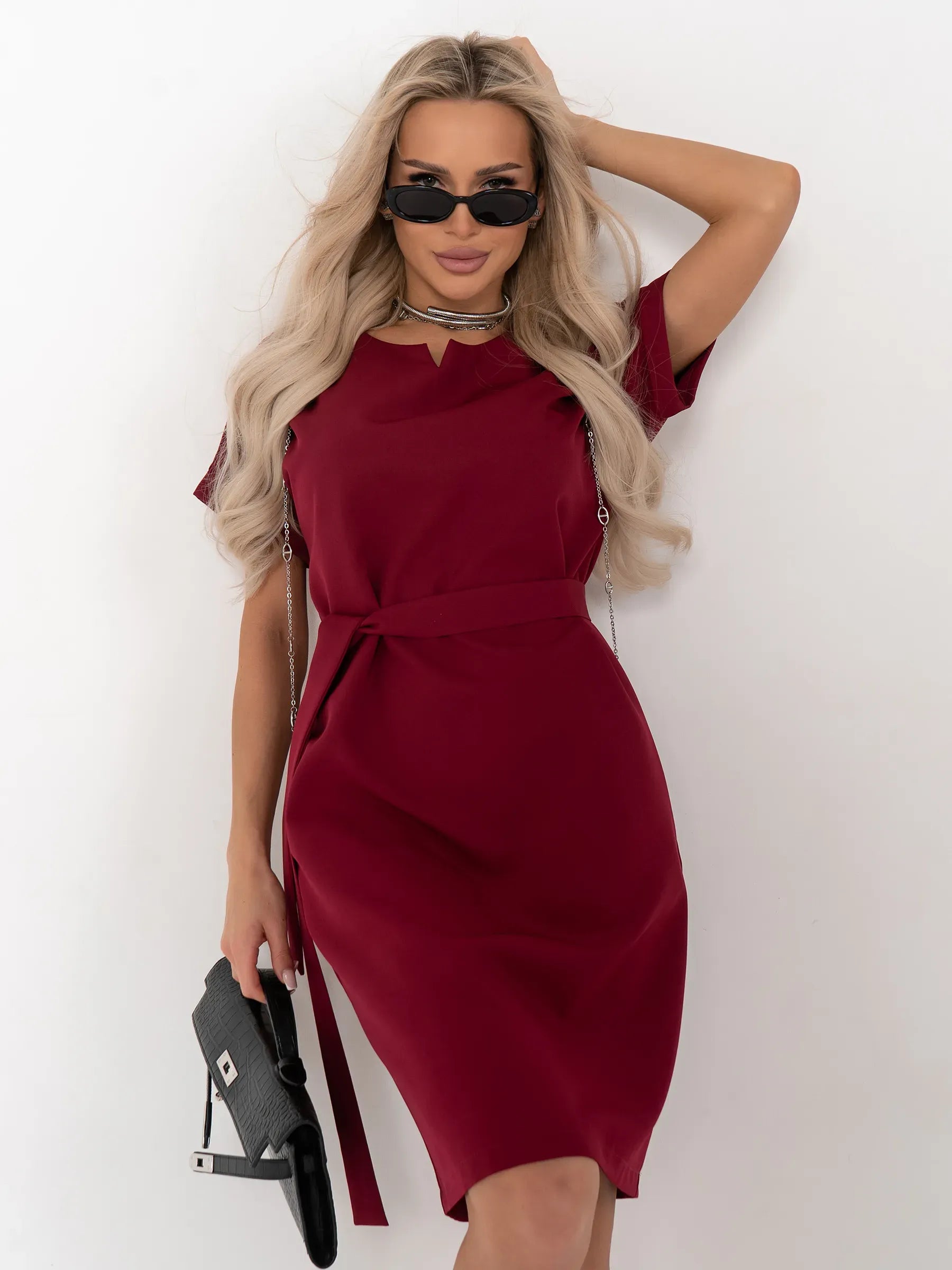 Model wearing the Crimson Code mini dress in wine-red, showcasing a structured design with a detachable belt and stylish accessories.