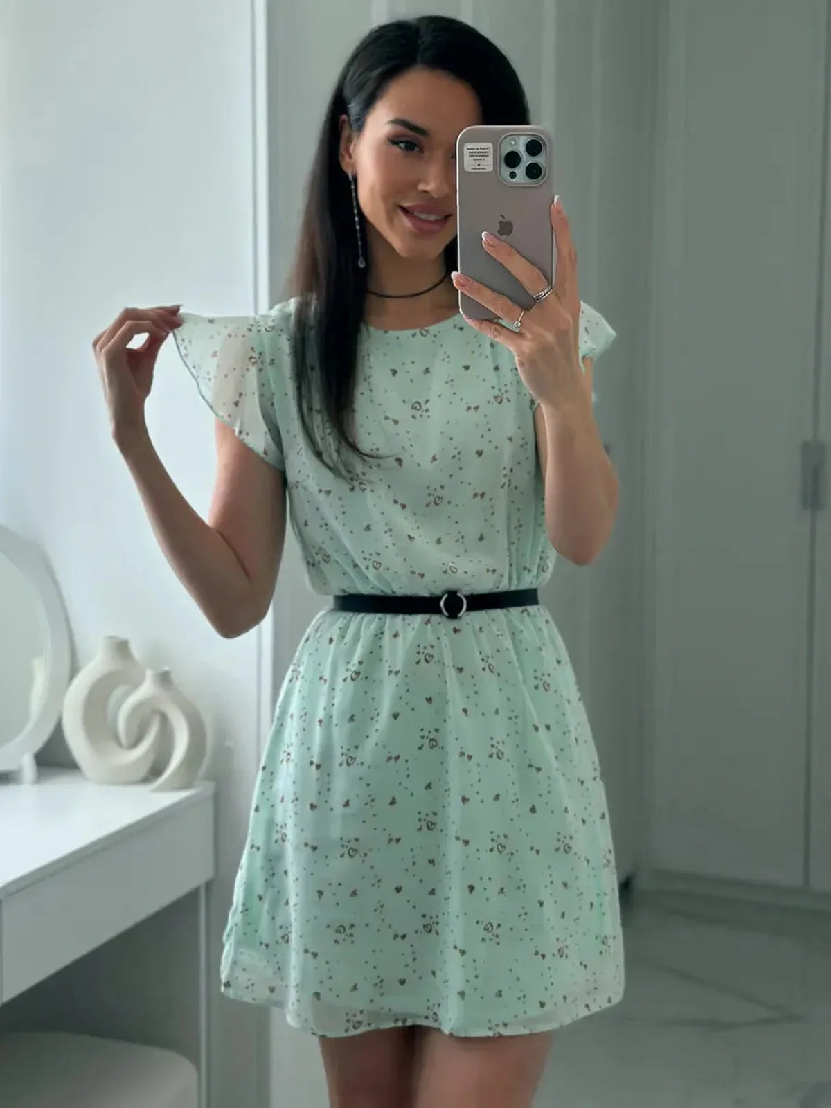 Model showcasing the Mint Glow Mini Dress, a light chiffon summer dress with fluttery sleeves and a cinched waist.