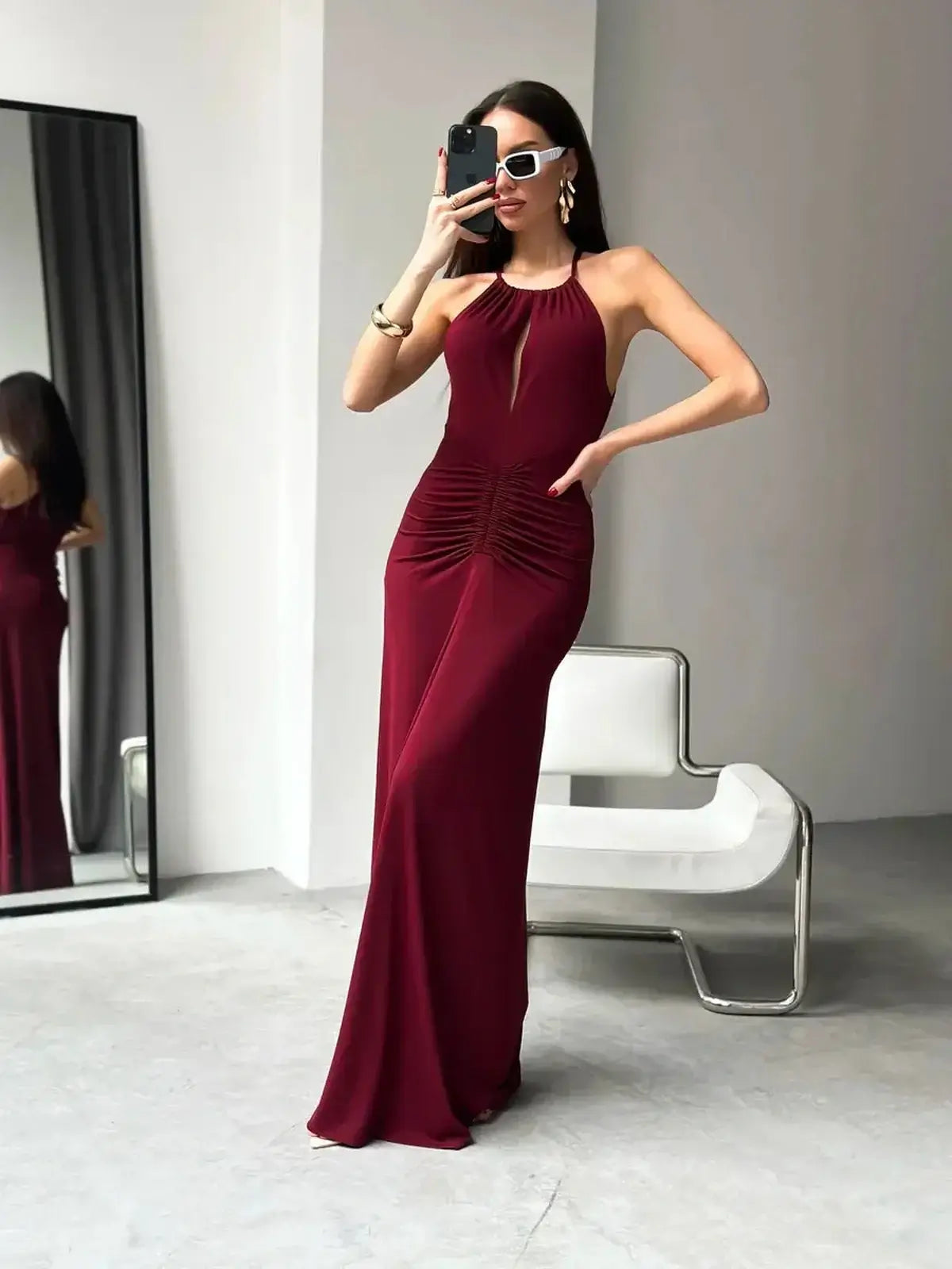 Woman in a burgundy halter maxi dress with ruched waist, ideal for formal events or wedding guest attire.