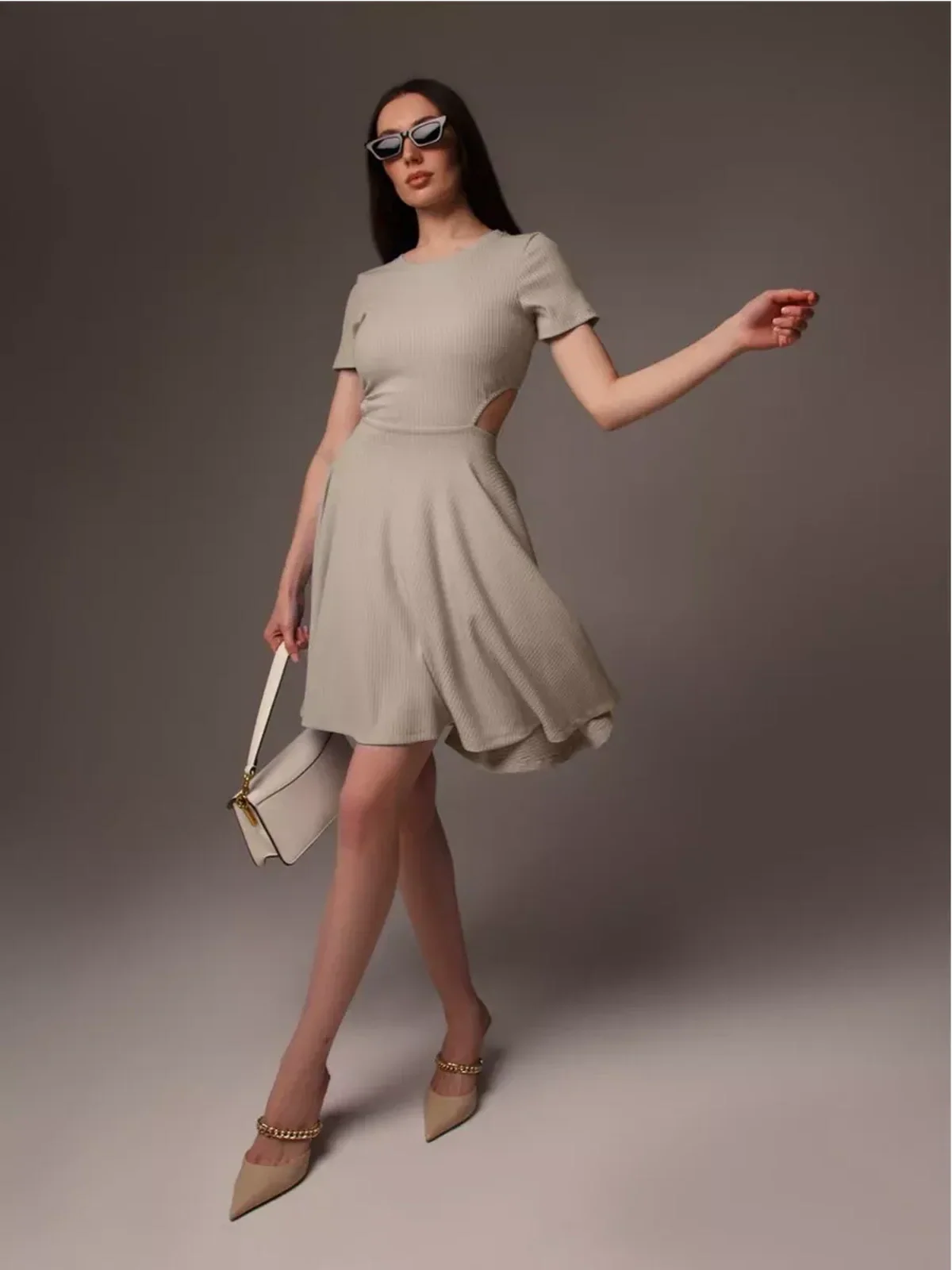 Model in a Breezy Hour mini dress with a flared hem and cutout, accessorized with sunglasses and a handbag.