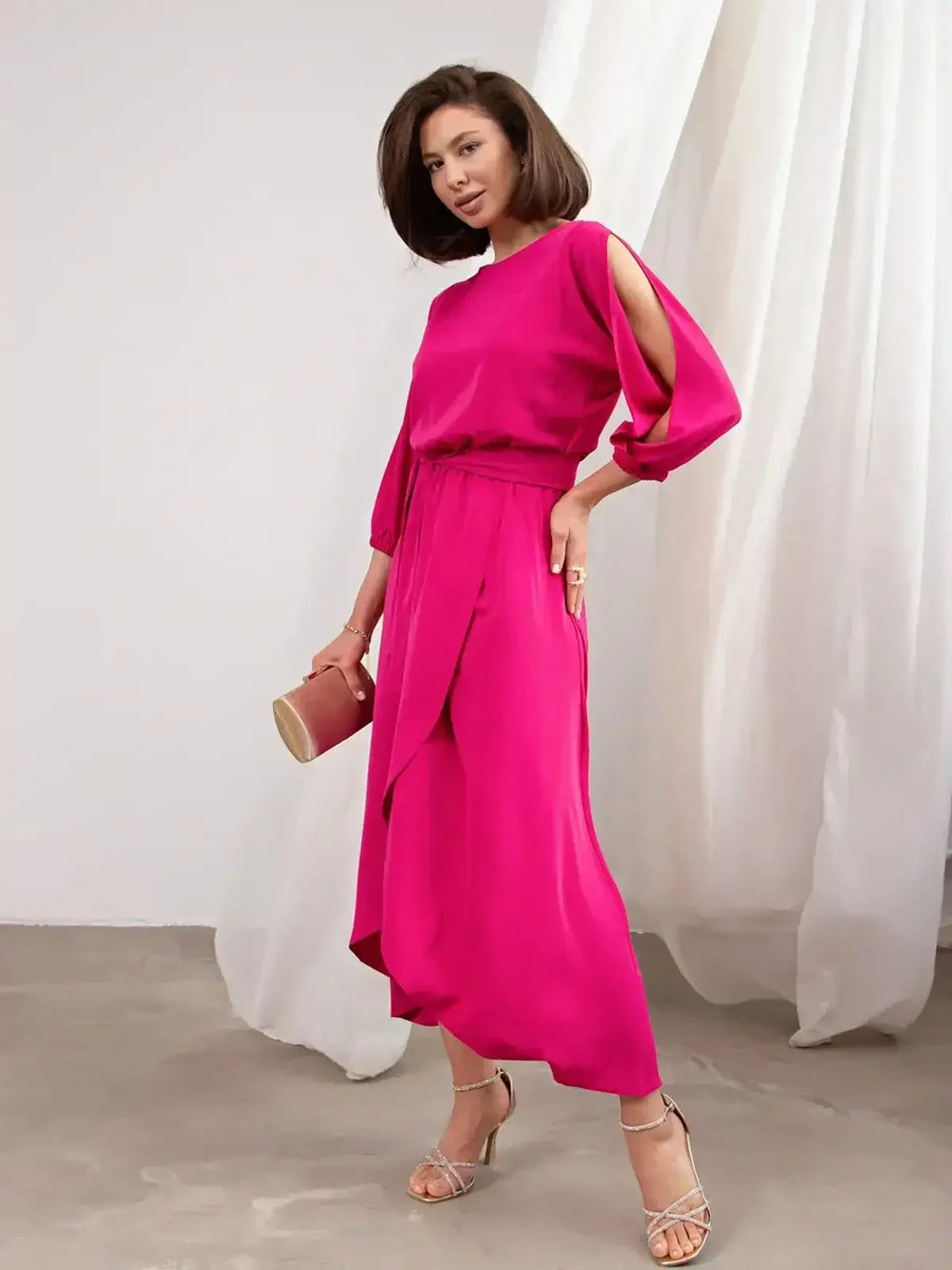 Model wearing the Twilight Bloom Midi Dress in fuchsia with shoulder cutouts, featuring a high-low hemline and elegant belt.