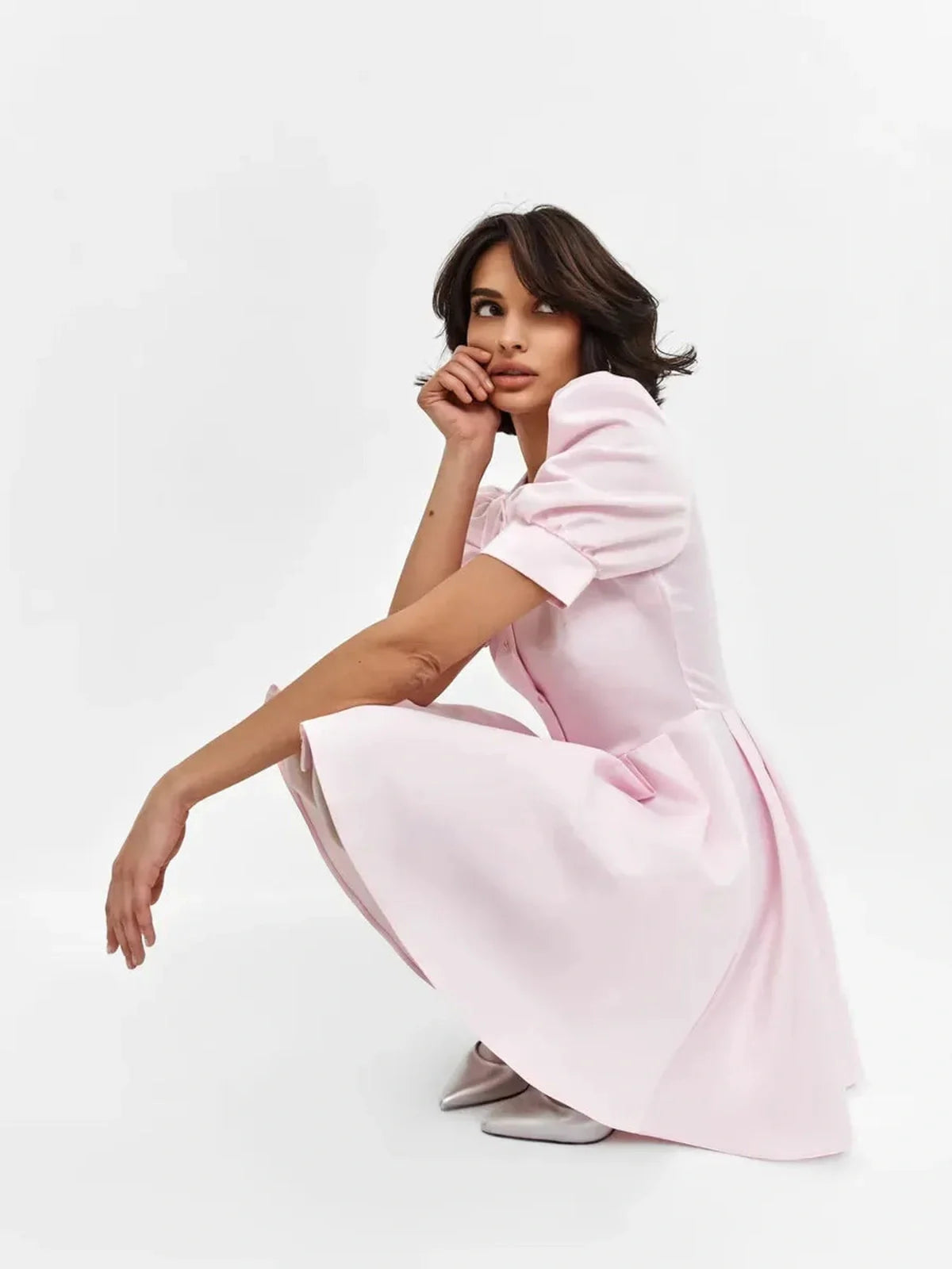 Woman in a pink Pearl Puff Mini Dress with statement sleeves, showcasing a stylish and feminine silhouette.
