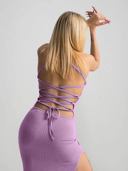 Back view of a woman in a lilac lace midi dress showcasing a corset style and high side slit, perfect for summer events.