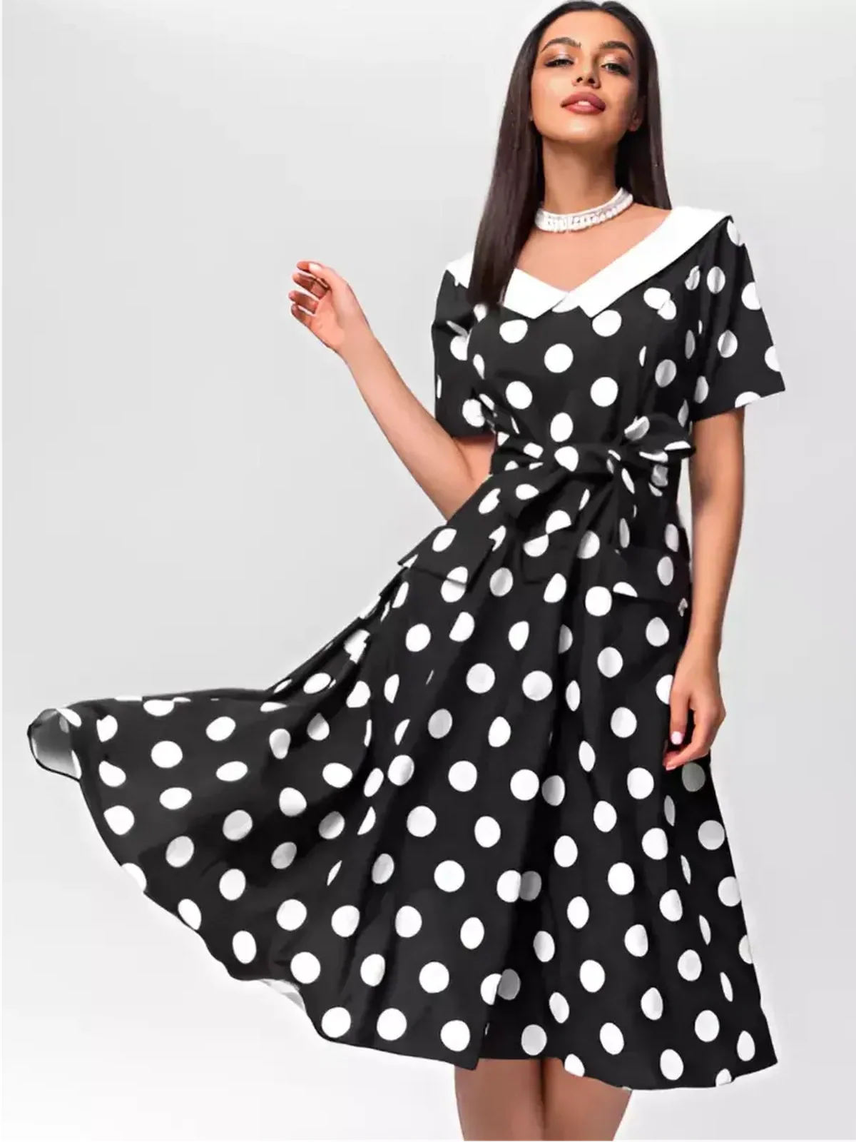 Elegant black and white polka dot midi dress with V-neckline and waist tie, perfect for summer occasions.