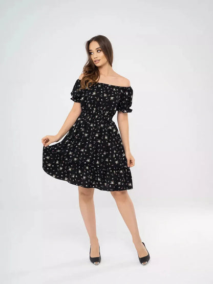 Model showcasing the Midnight Bloom black floral mini dress with off-shoulder neckline and puff sleeves.