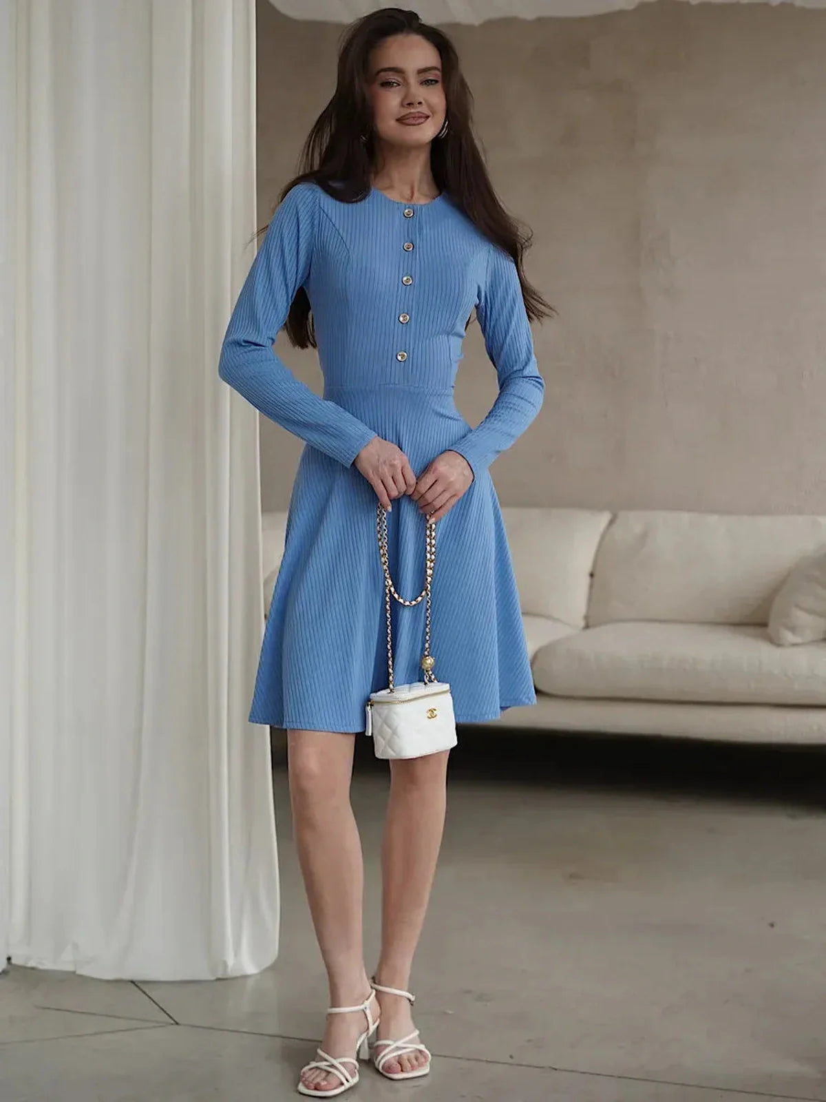 Woman wearing a soft sky-blue mini dress with long sleeves, ribbed knit, and button placket, perfect for summer or casual events.