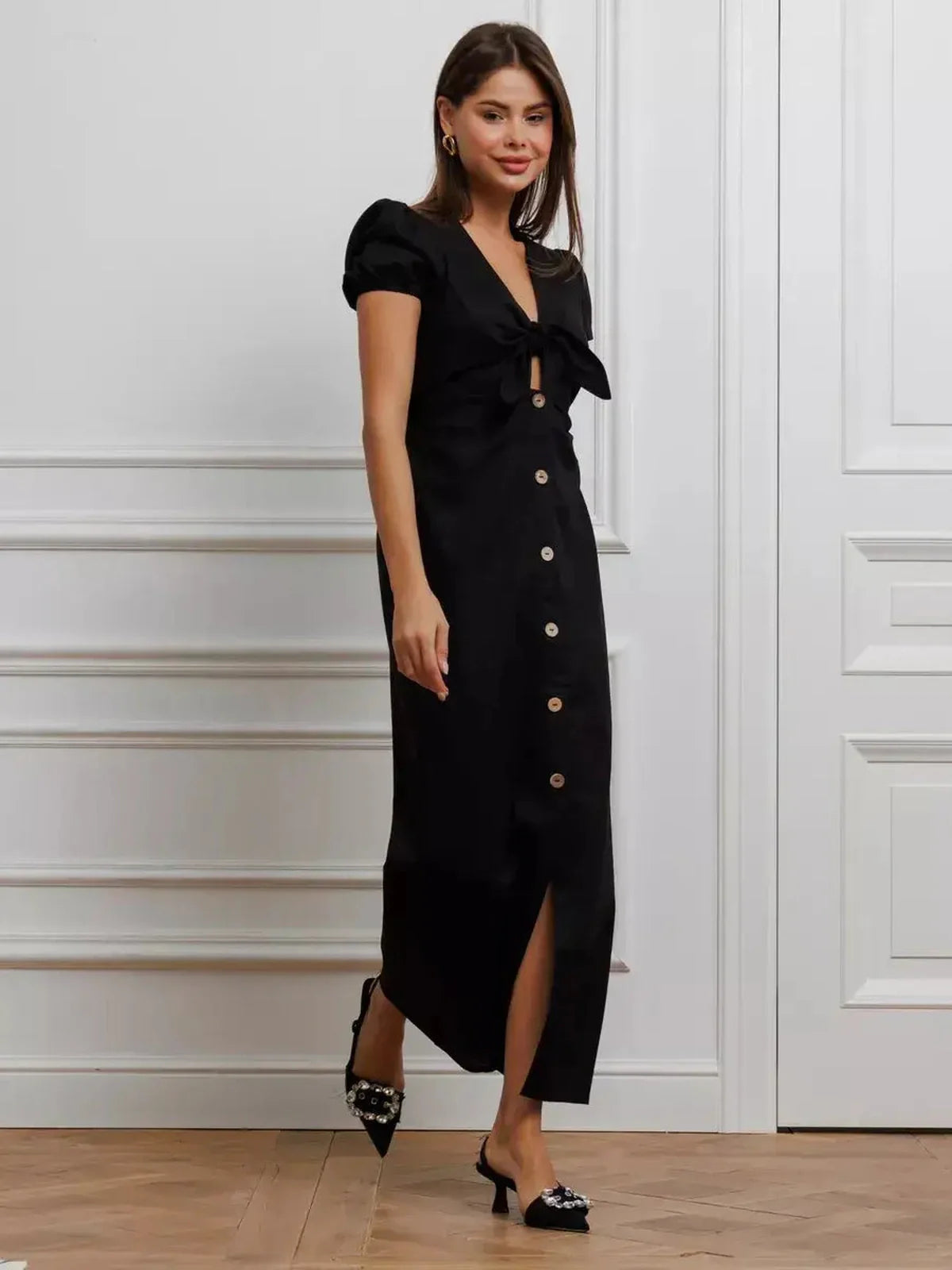 Maxi Dress Noir Belle – Elegant black maxi dress with tie-front, puff sleeves, and button detail, perfect for summer weddings and events.