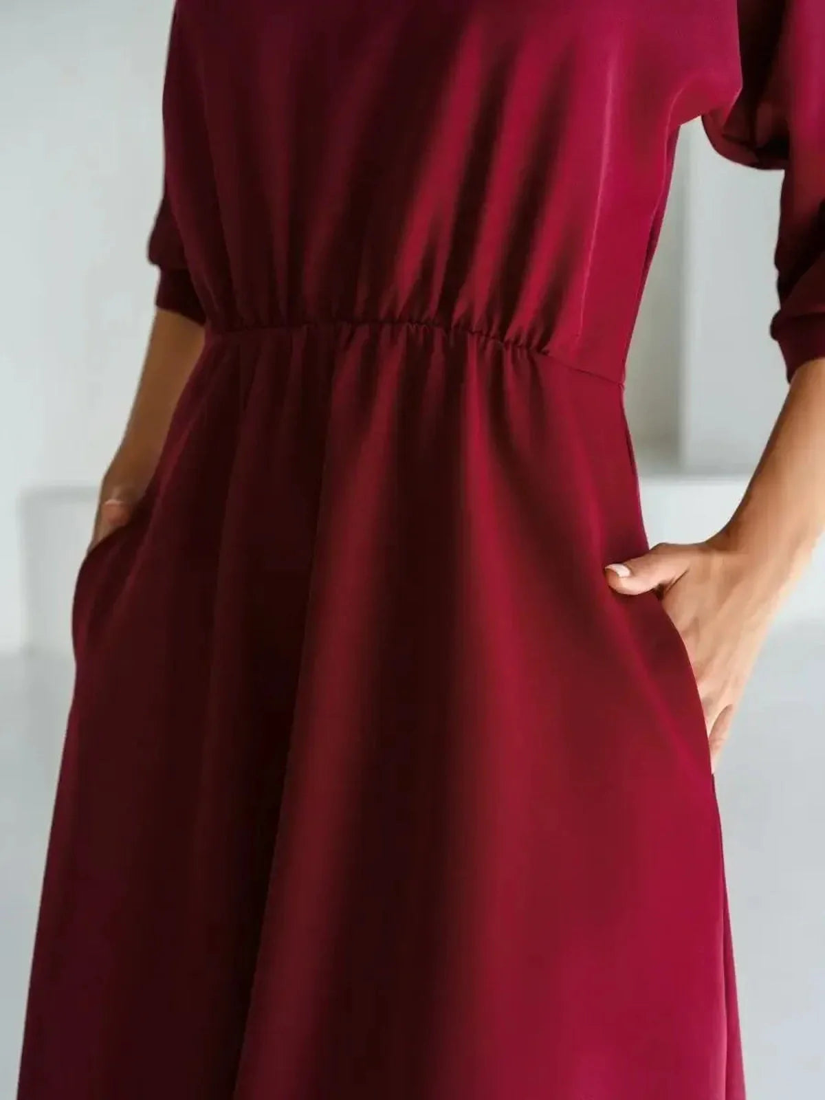 Close-up of the Crimson Grace Midi Dress showcasing its elegant burgundy fabric and cinched waist with pockets.