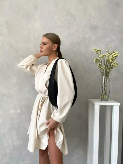 Model showcasing the Ivory Whisper mini dress, featuring long sleeves and a flattering V-neckline against a neutral backdrop.