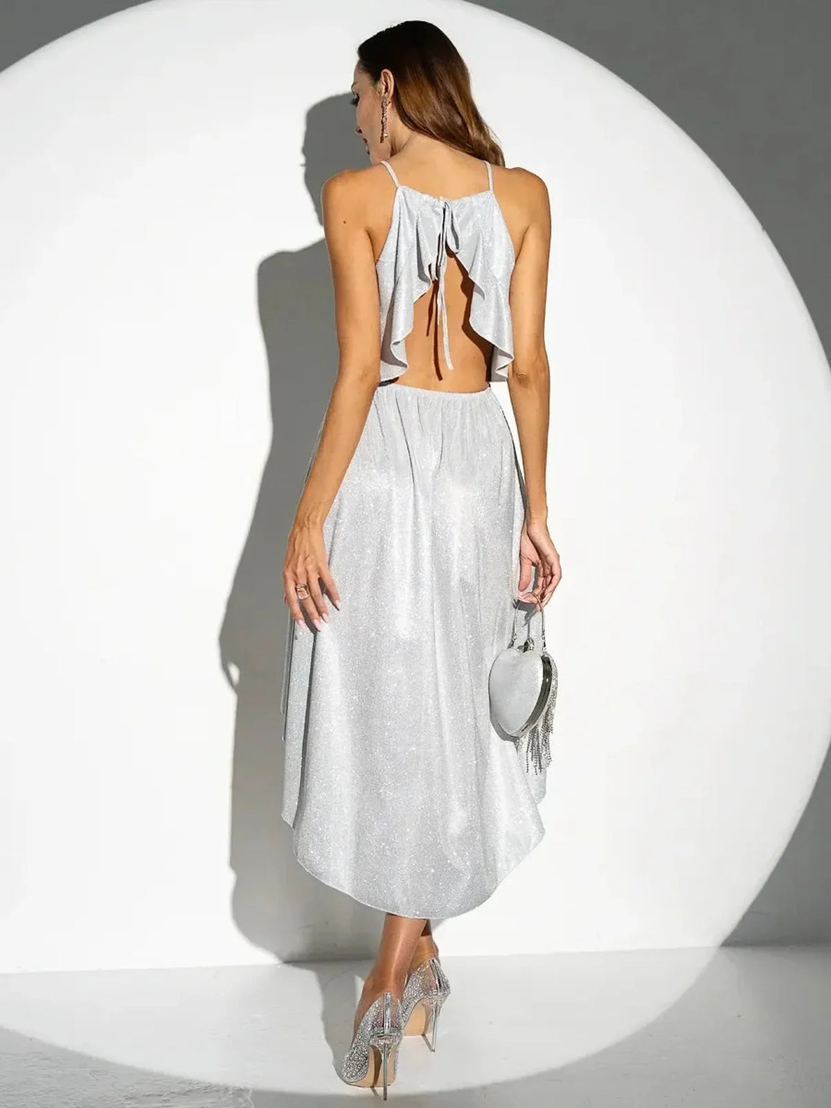 Back view of a woman in a Celestial Glow Midi Dress with ruffles and a sparkling silver finish, perfect for weddings and formal events.