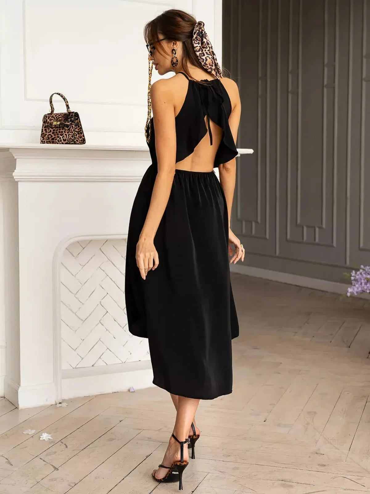 Sleek black Soirée Midi Dress with open back and halter neckline, perfect for summer weddings and formal events.
