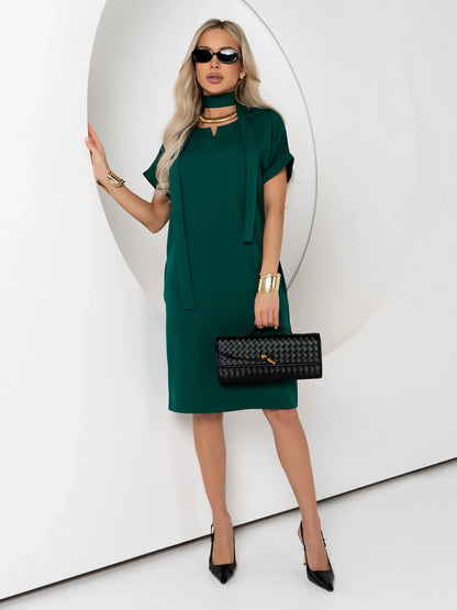 Stylish woman in a green mini dress with cuffed sleeves and a belt, perfect for summer, weddings, or formal events.