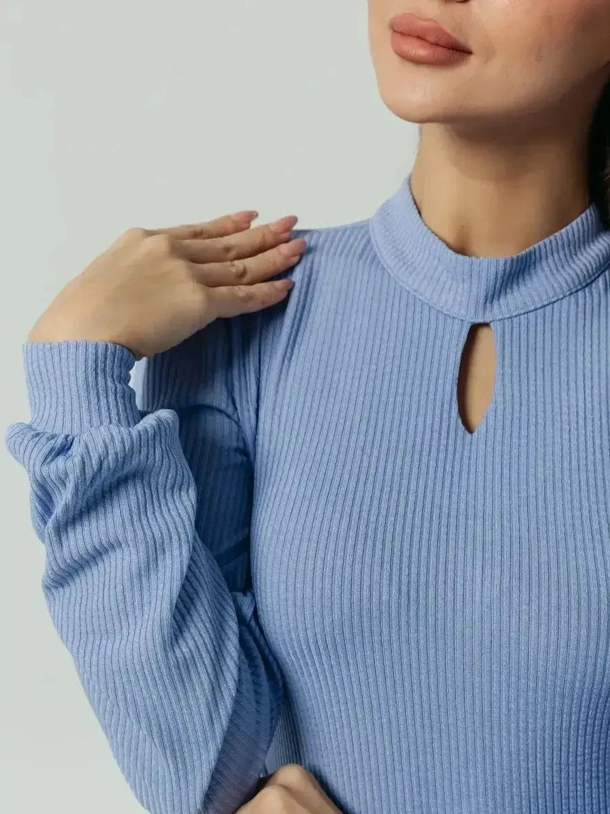 Close-up of a model showcasing the Elegance Midi Dress in powder blue with a keyhole neckline and pleated long sleeves.