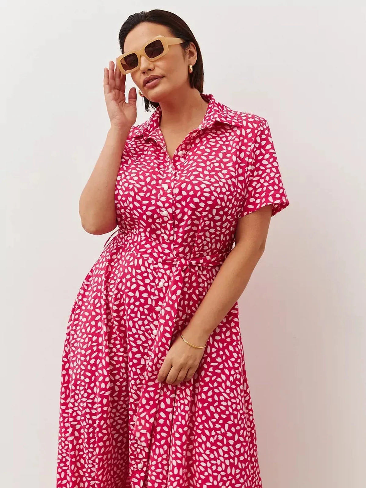 Model wearing the Petal Pop Midi Dress, a vibrant pink dress with white petal print, perfect for summer occasions.