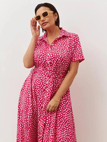 Model wearing the Petal Pop Midi Dress, a vibrant pink dress with white petal print, perfect for summer occasions.