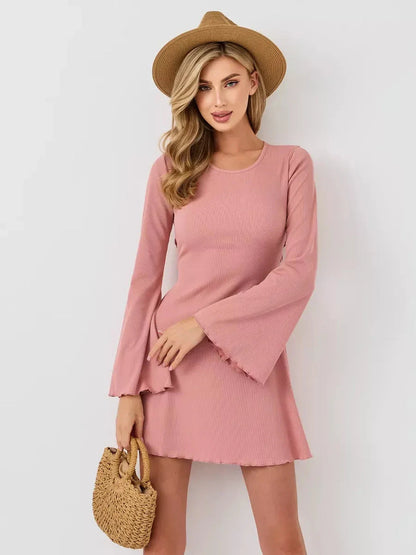 Stylish woman in a Blush Aura mini dress with long flared sleeves and a U-neckline, perfect for summer outings.