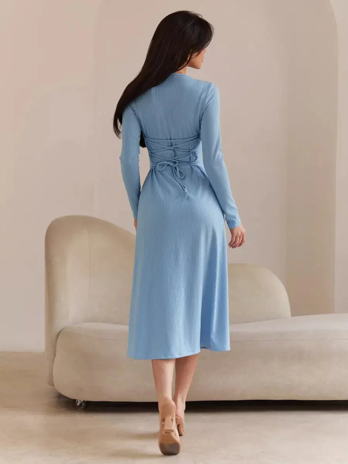 Back view of a woman in a light blue midi dress featuring corset-style ties, perfect for summer events and weddings.