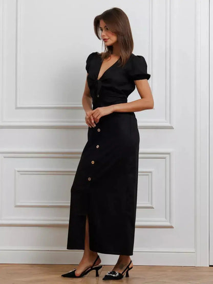 Elegant black maxi dress with tie-front detail, puff sleeves, and contrast buttons, perfect for weddings and formal events.