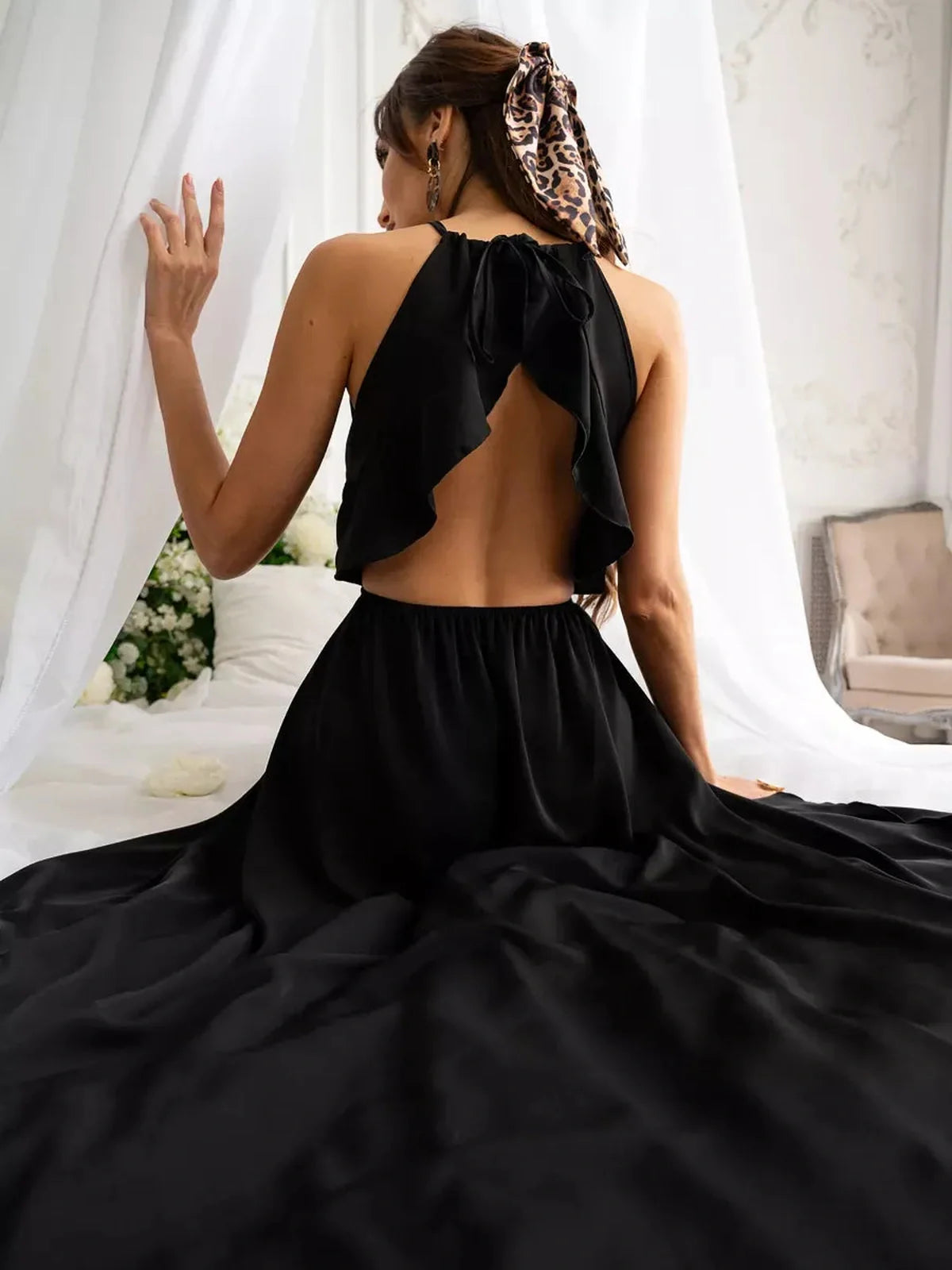 Elegant open back of the Soirée Midi Dress in black, showcasing its flowing A-line silhouette and halter neckline.