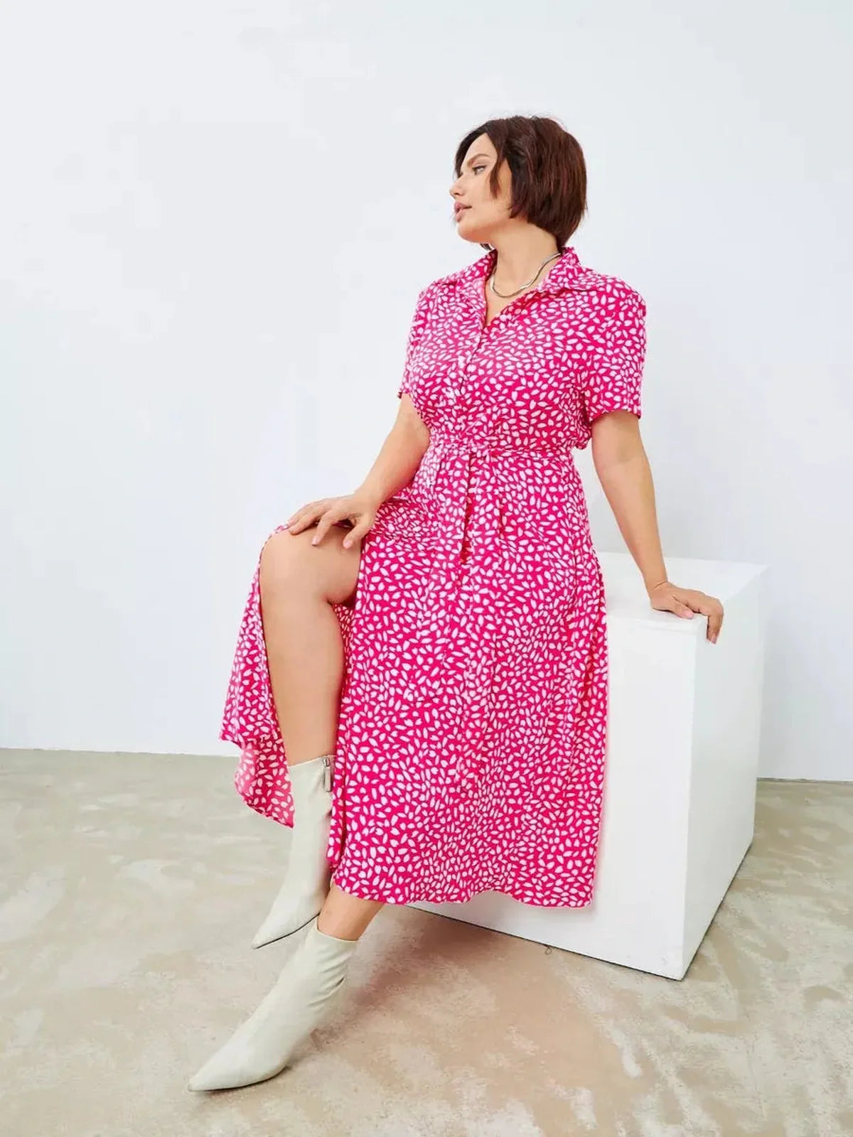 Model wearing a vibrant fuchsia Petal Pop Midi Dress with white petal print, styled for casual elegance.