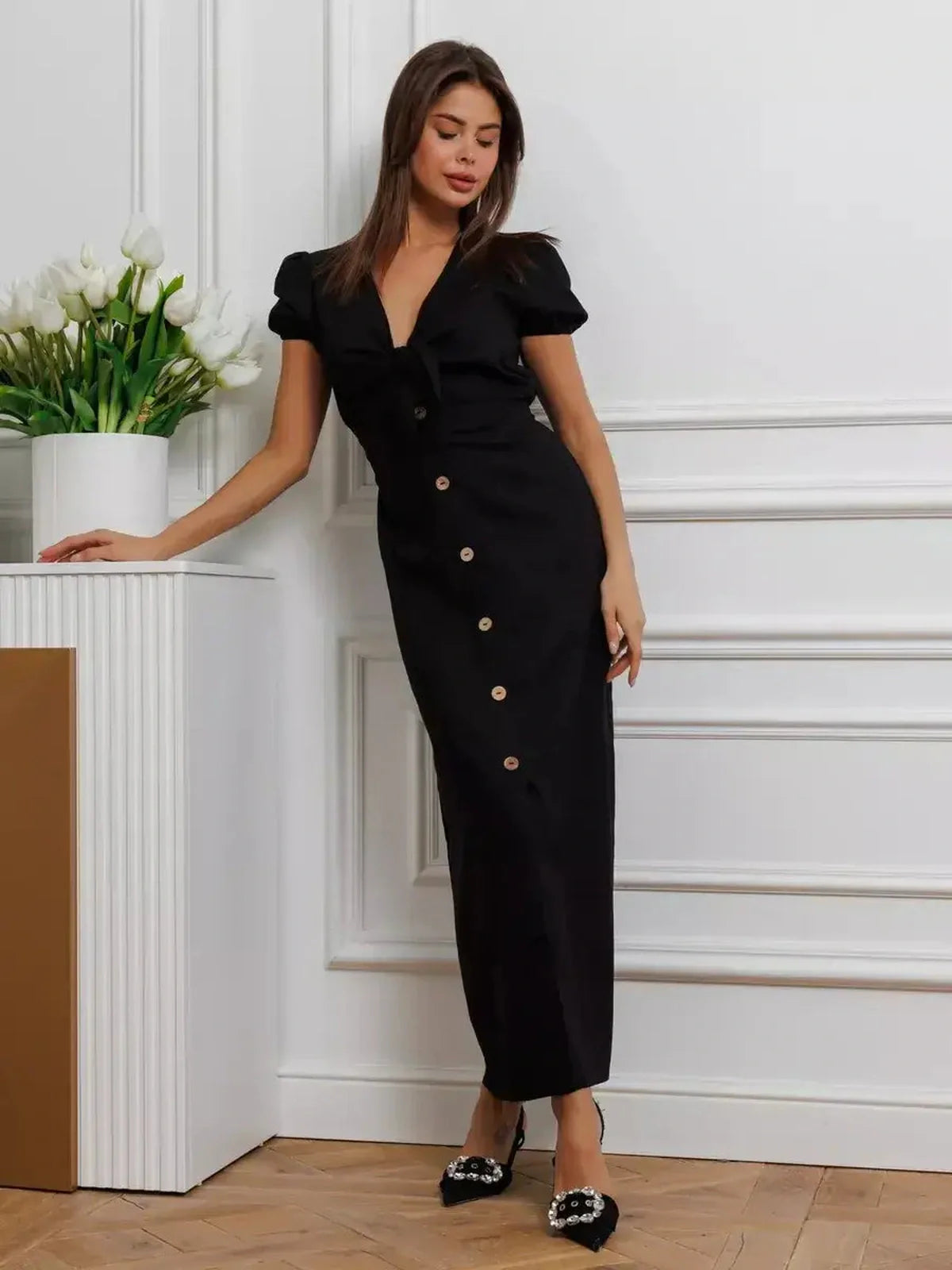 Elegant black maxi dress with tie-front detail, flattering V-neckline, and puff sleeves, perfect for weddings and formal events.