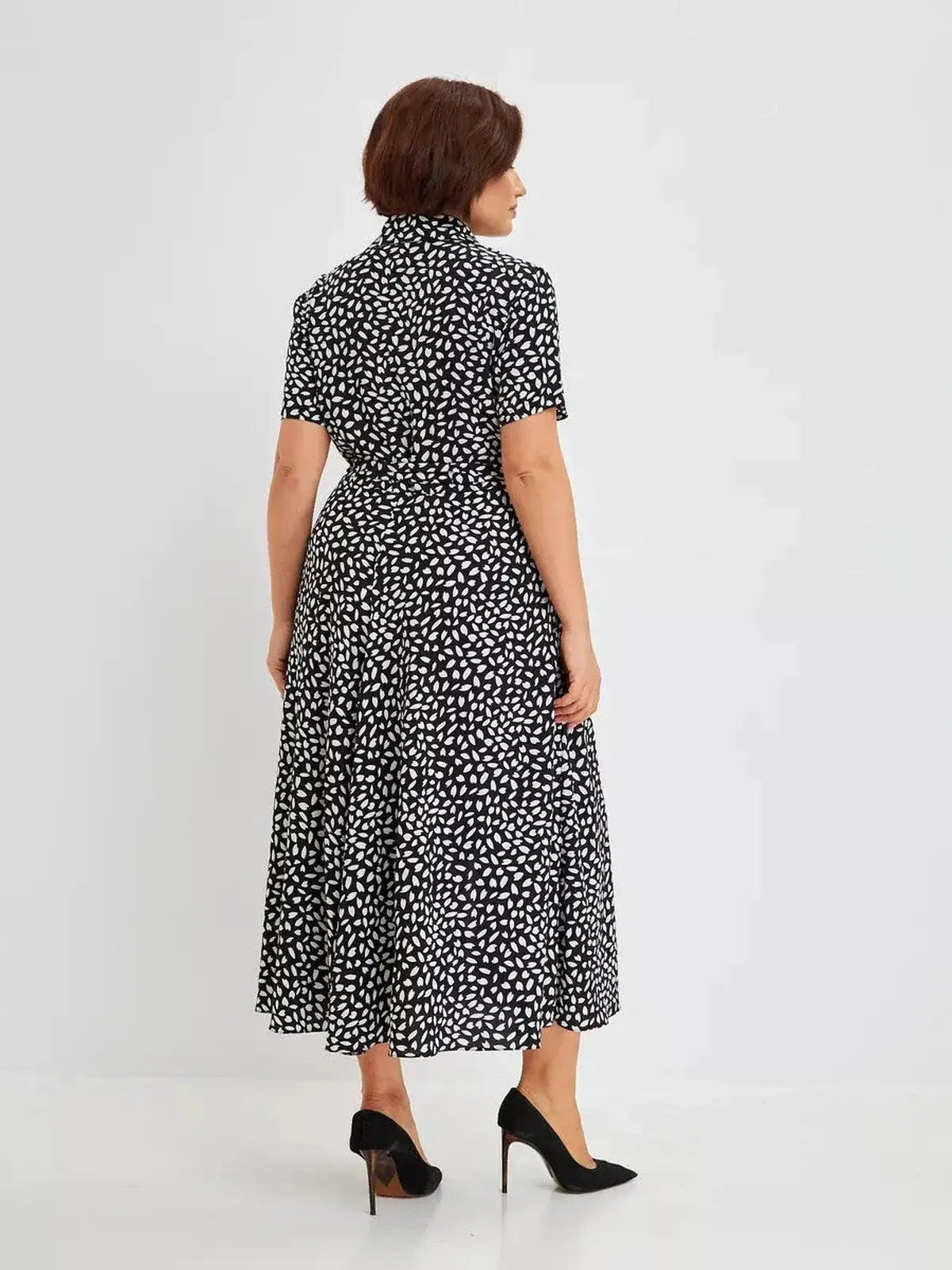 Back view of a woman in the Monaco Midi Dress, featuring a black and white abstract print and a flattering silhouette.