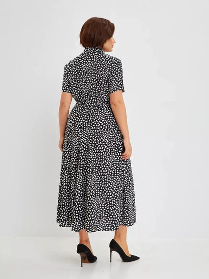 Back view of a woman in the Monaco Midi Dress, featuring a black and white abstract print and a flattering silhouette.
