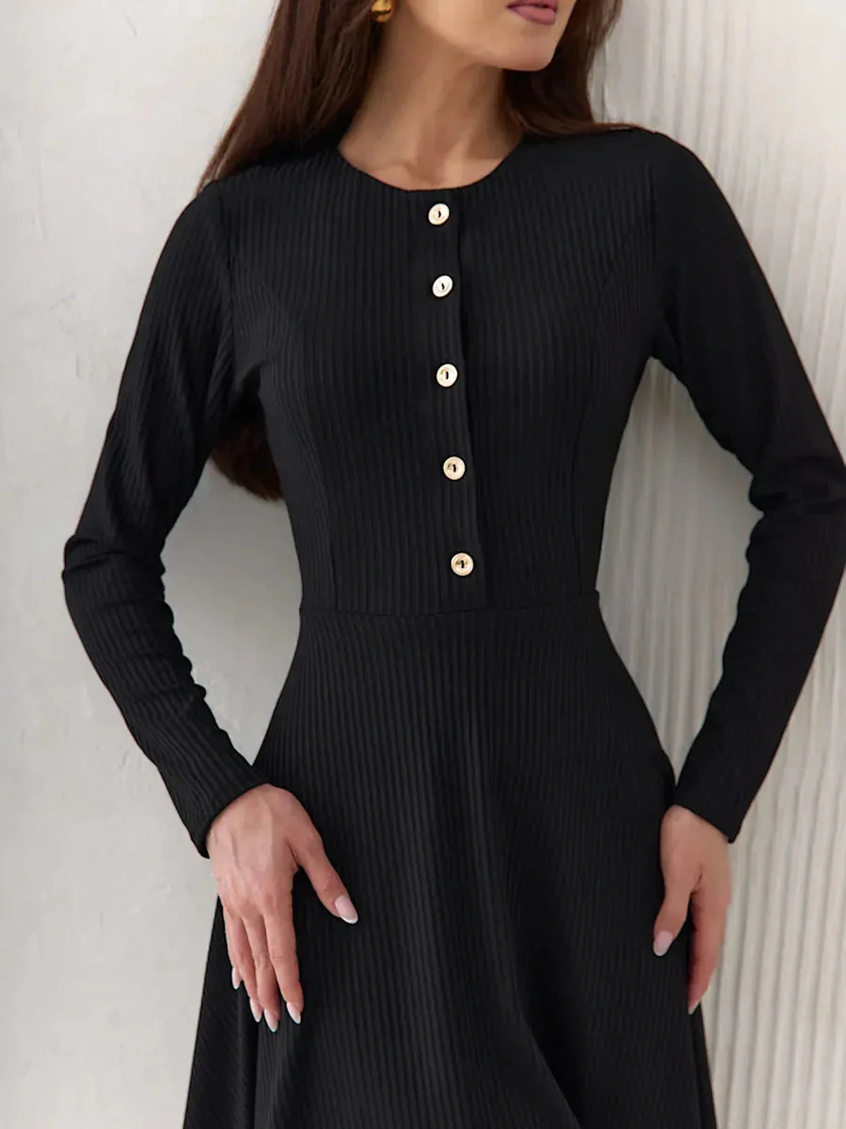 Effortless elegance in a black ribbed mini dress with long sleeves and statement buttons, perfect for various occasions.