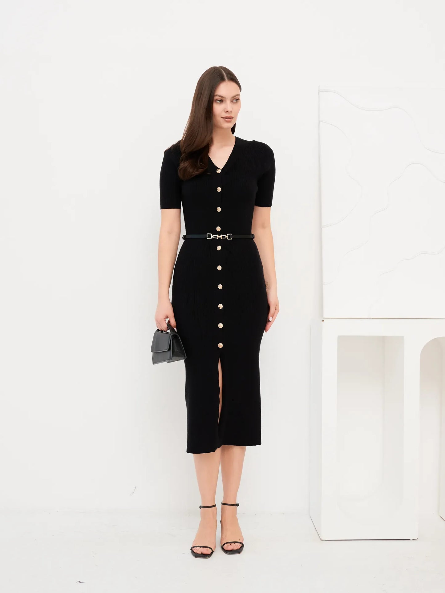 Woman wearing the Sculpted Grace Midi Dress, featuring a fitted black rib knit and gold button accents.