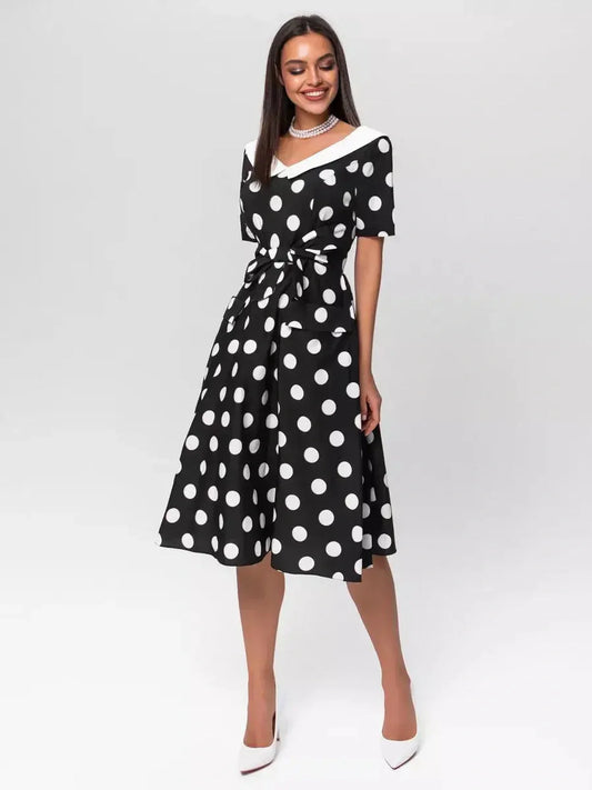 Elegant black-and-white polka dot midi dress with V-neck and waist tie, perfect for weddings and summer occasions.
