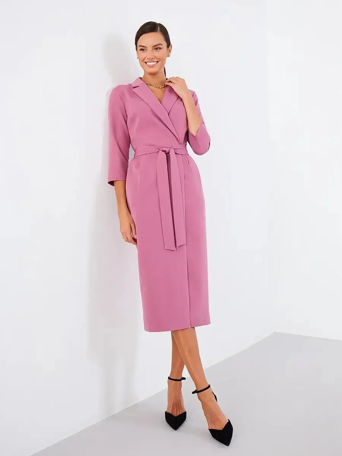 Woman wearing a blush wrap midi dress with a belted waist and three-quarter sleeves, perfect for formal and casual occasions.