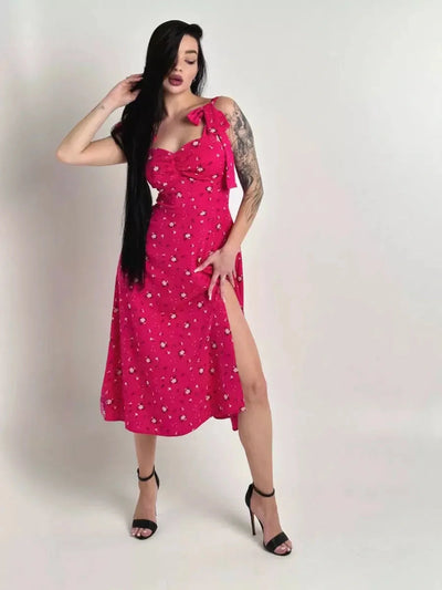 Model wearing the Rosé Charm Midi Dress featuring a pink floral print and sweetheart tie detail.
