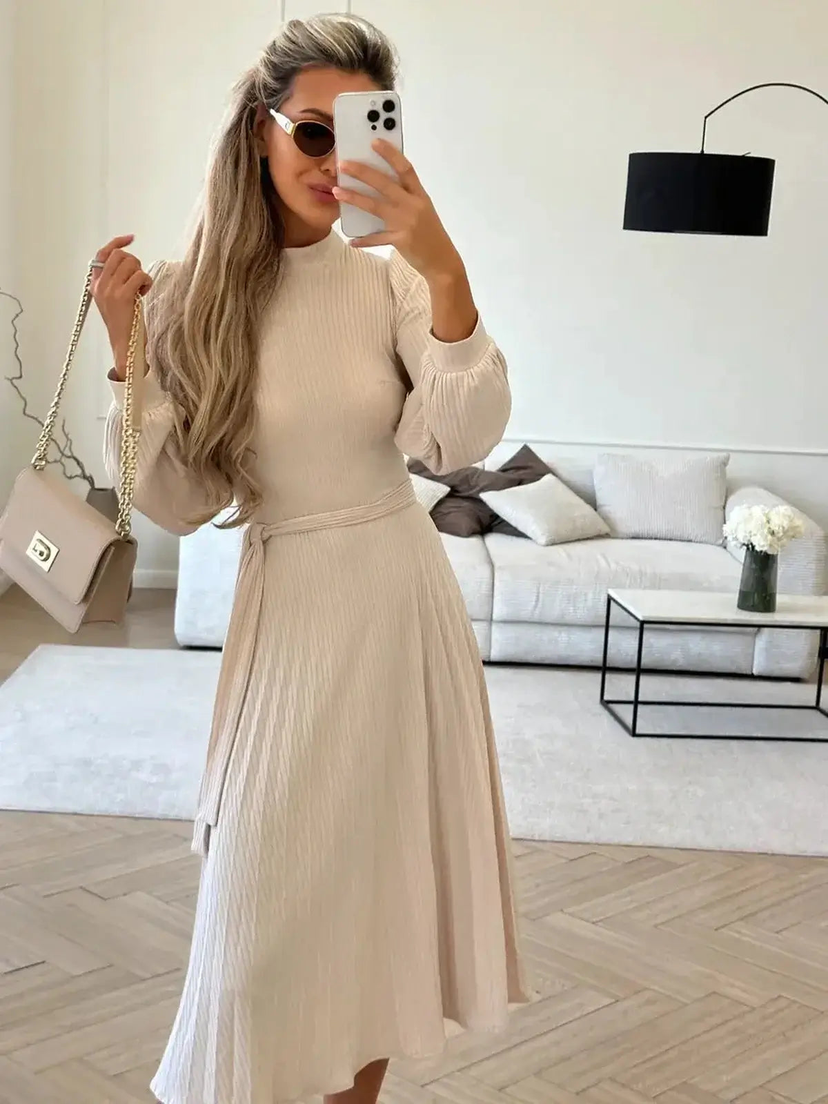 Woman in an Ivory Whisper Midi Dress, featuring ribbed knit texture and flowing skirt, perfect for weddings or casual events.
